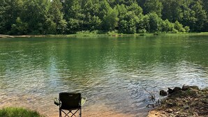 A lakeside view with a chair by the water's edge.