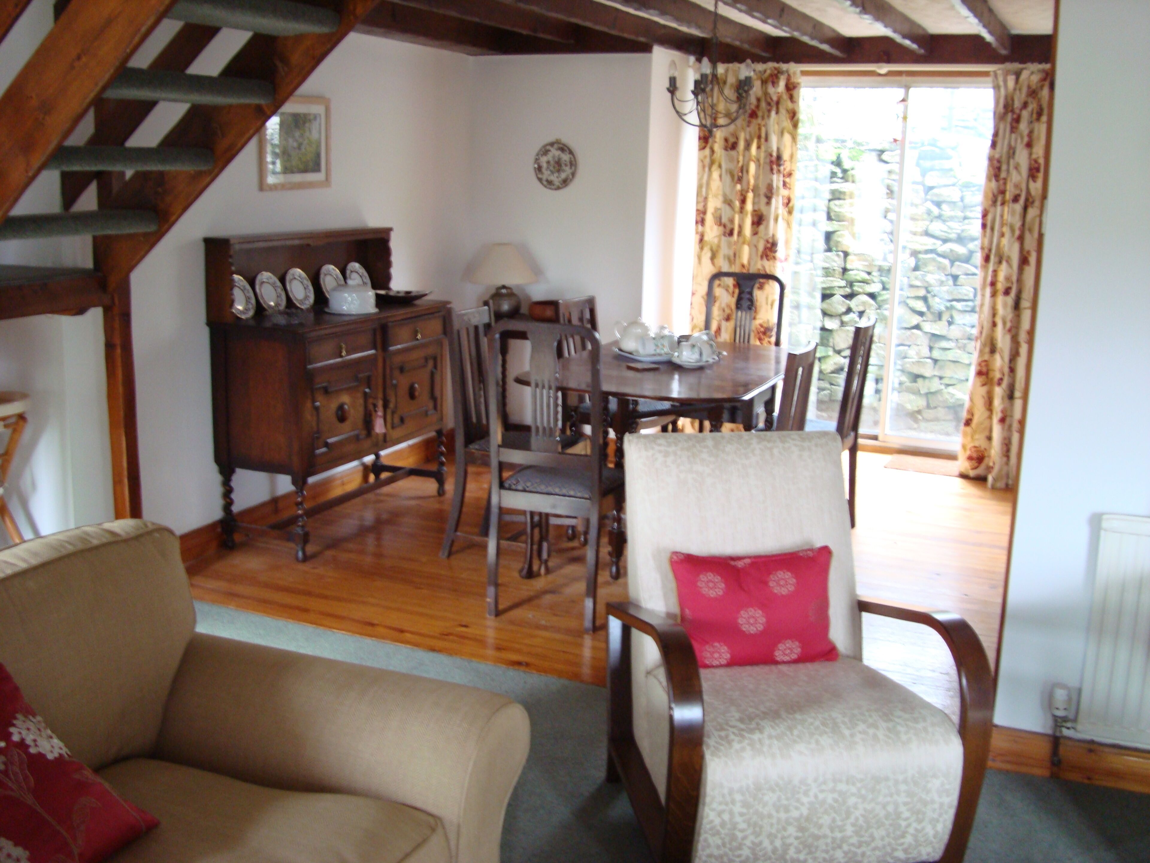 A dining area with a wooden table, chairs, and a cabinet with clocks.