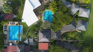 A resort with multiple swimming pools, palm trees, and thatched-roof structures.