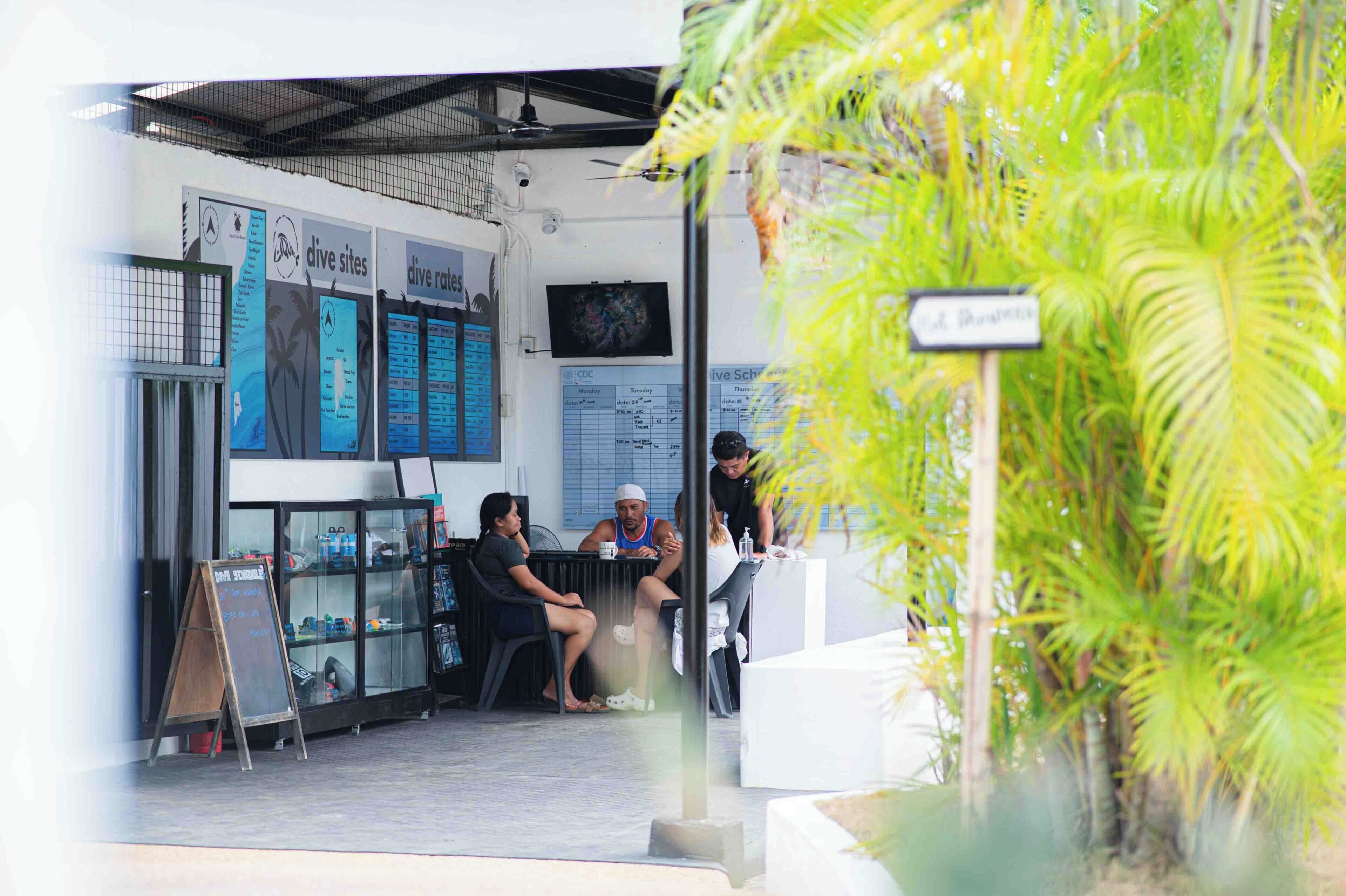 A cafe with outdoor seating, a menu board, and a sign indicating a nearby location.