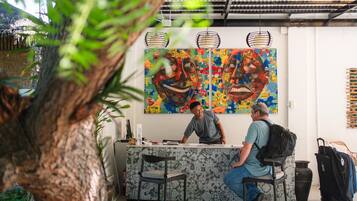 Un área de recepción con mostrador, dos sillas y un cuadro abstracto grande en la pared.