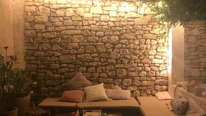 A cozy outdoor seating area with a stone wall backdrop, a cushioned sofa, and a small table with a drink. - Charming village house in Aix en Provence (Aix en Provence)
