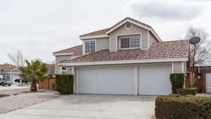 A two-story house with a garage, a satellite dish, and a well-maintained lawn. - Hill View Home of the High Desert Victorville CA (Victorville)