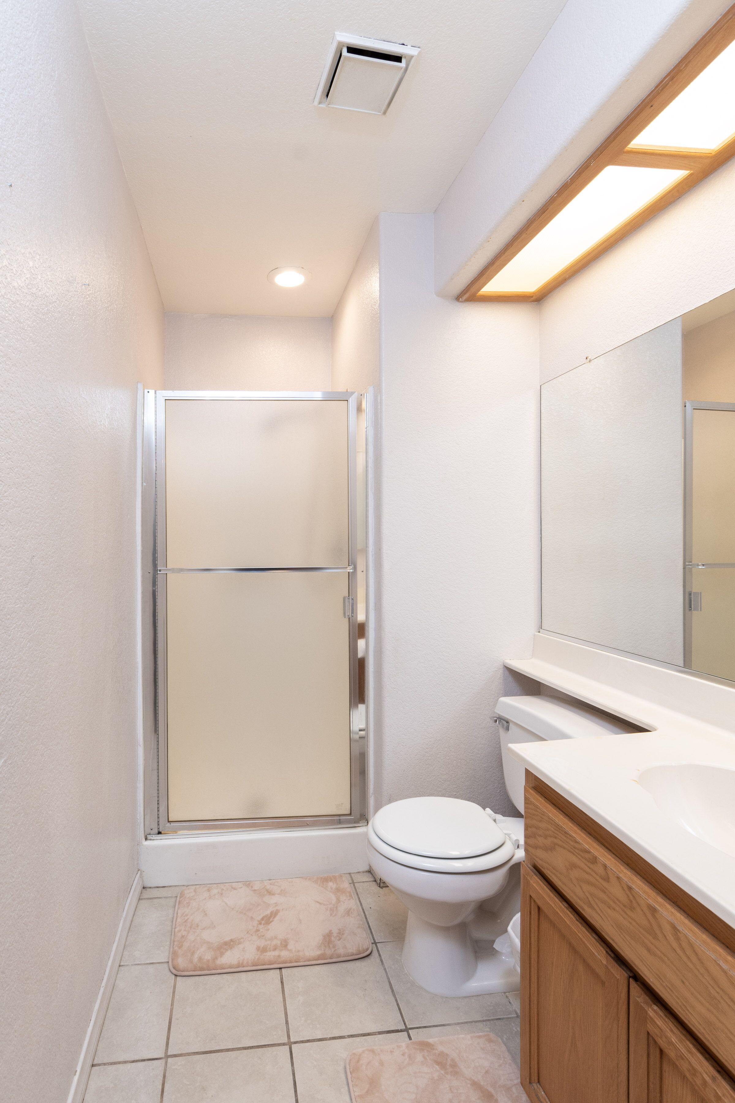 A bathroom with a shower, toilet, and vanity.