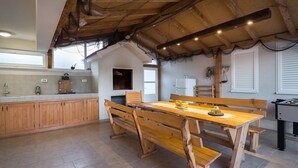 A rustic kitchen with wooden cabinets, a dining table with benches, and a foosball table.