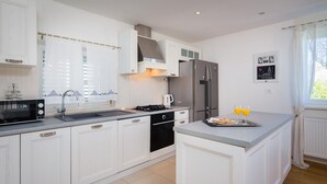 A modern kitchen with white cabinetry, a stainless steel refrigerator, a microwave, and a gas stove.