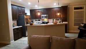 Une cuisine moderne avec des meubles en bois foncé, des appareils électroménagers en acier inoxydable et des luminaires suspendus.