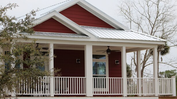 Une maison rouge et blanche avec un porche et un balcon.