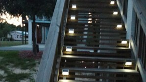 Un escalier en bois, dont les marches sont éclairées, mène à l’entrée d’un immeuble.