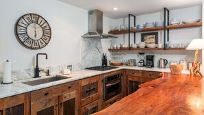 Une cuisine moderne dotée d’un plan de travail en marbre, de meubles en bois, d’un évier en acier inoxydable et d’un four encastré.