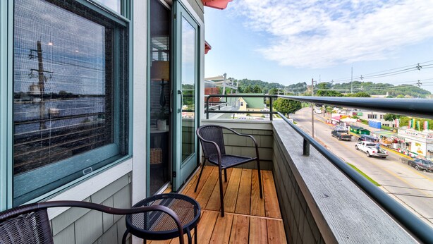 A balcony with a view of a busy street and hills in the background.