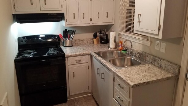 A kitchen with white cabinets, a black stove, granite countertops, a sink, and a window with blinds. - Great location! 5 min. to Downtown, Medical District, and the Masters. (Augusta)