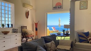 Ein Wohnzimmer mit Sofa, Sessel, Tisch und Meerblick.