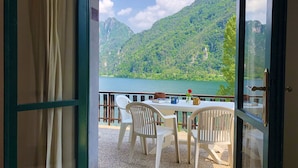 A room with a table and chairs facing a scenic mountain view and lake. - Directly on the lake with terrace (Tre Capitelli)
