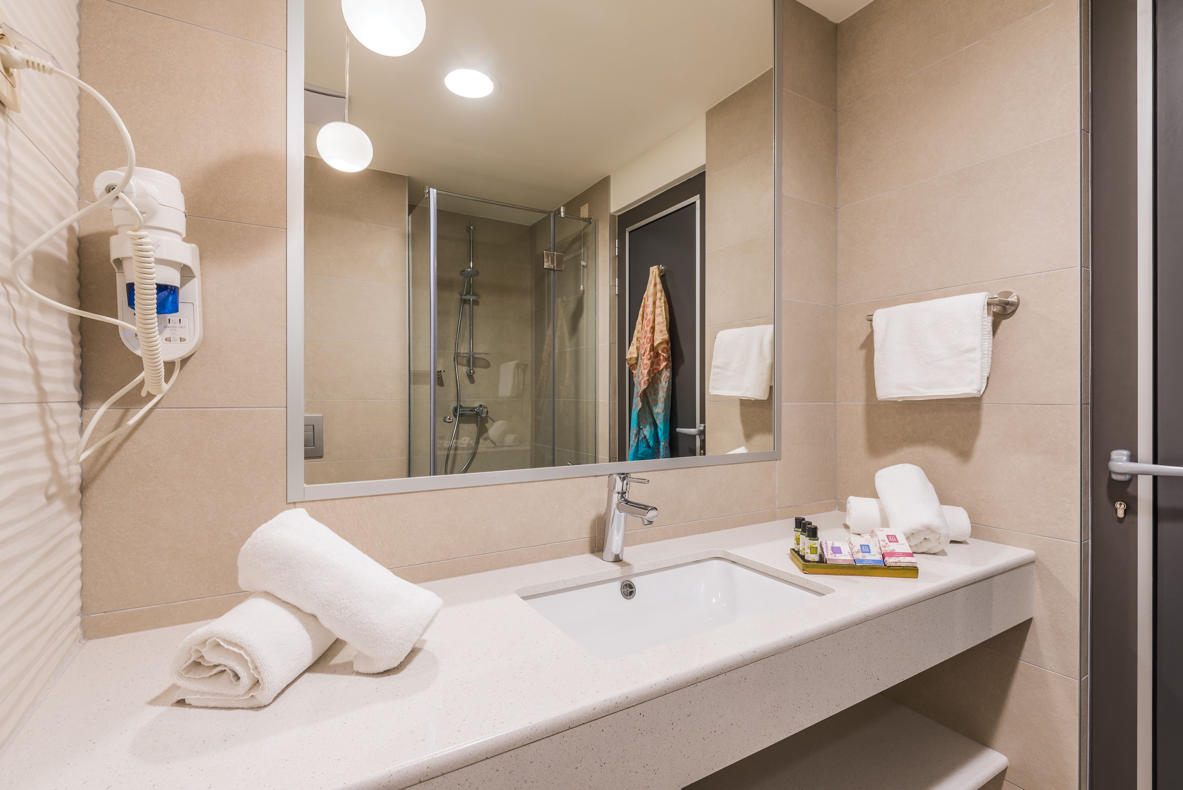 Une salle de bain moderne avec un grand miroir, un lavabo et un espace douche.