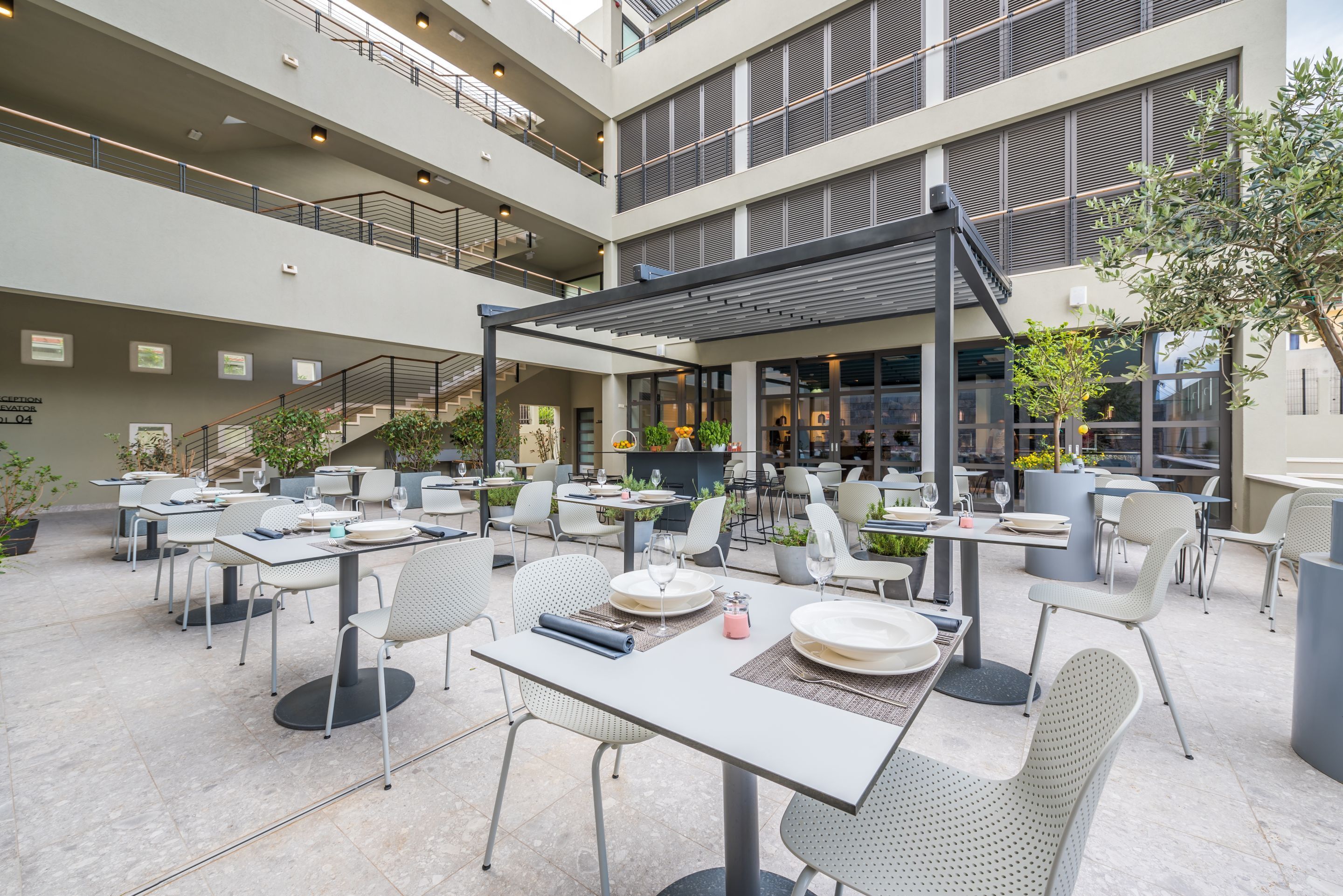 A multi-level outdoor dining area with tables and chairs, a covered seating area, and a staircase leading to an upper level.