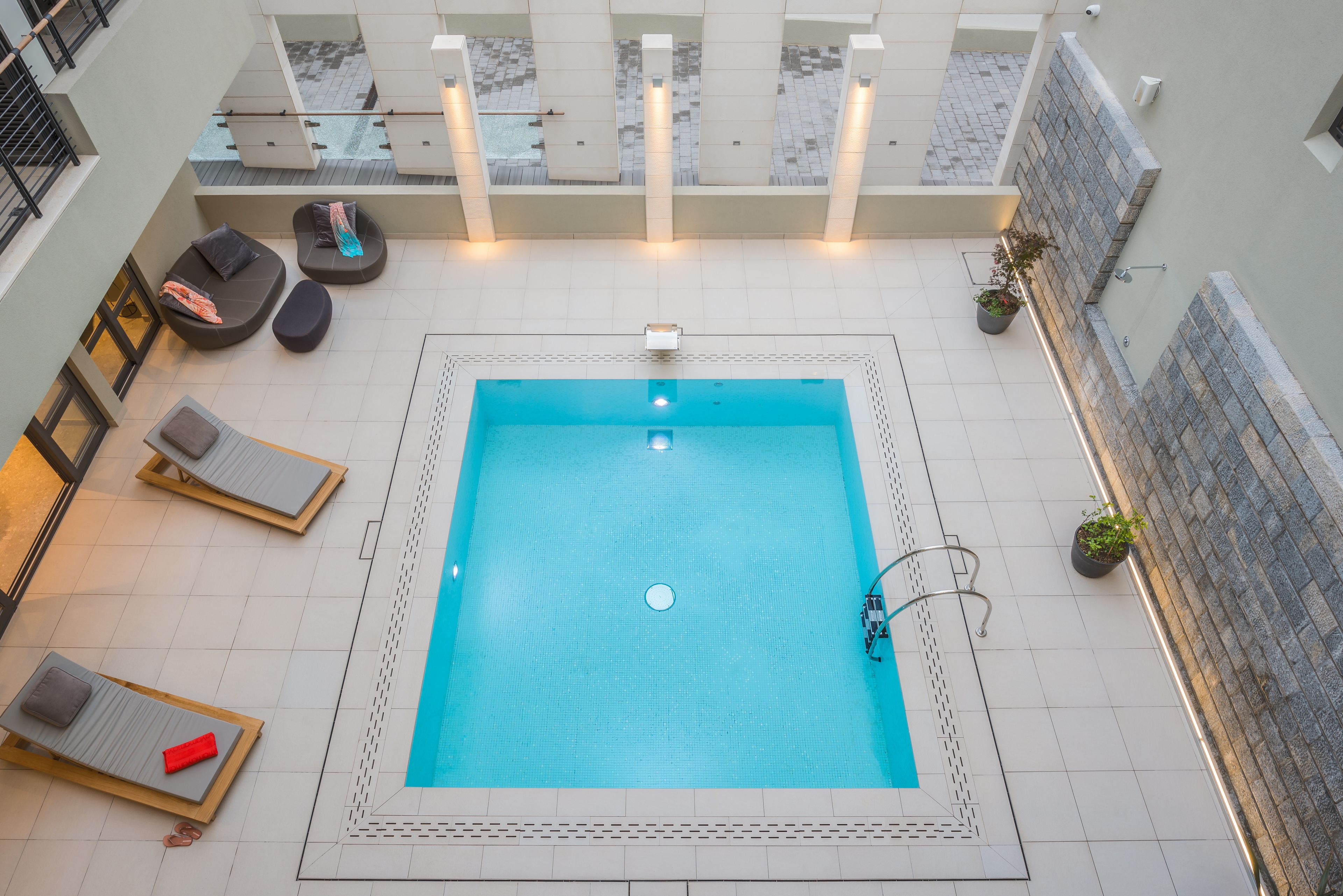 Et tagområde med swimmingpool, liggestole og plantekrukker.