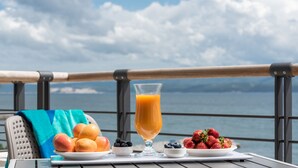 A table with fruit and a glass of orange juice on a balcony with a view of the sea. - Hotel Nestos (Dugi Rat)