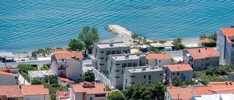 Un quartier résidentiel situé sur la côte, avec des immeubles modernes, un littoral rocheux et une vue dégagée sur la mer.