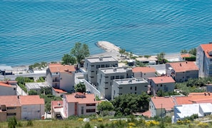 A coastal residential area with modern buildings, a rocky shoreline, and a clear view of the sea. - Hotel Nestos (Dugi Rat)