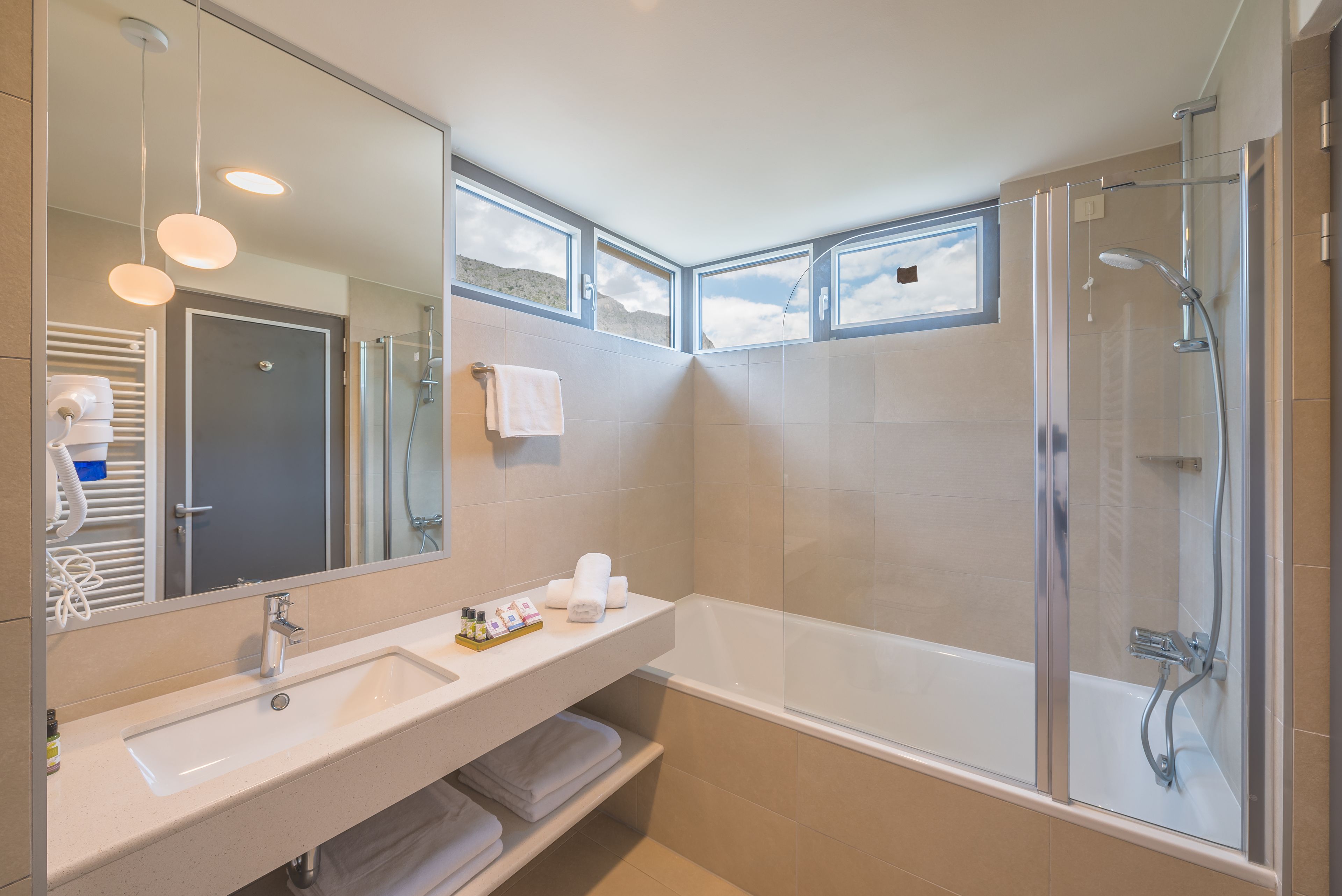 Une salle de bain moderne avec un grand miroir, un lavabo, une douche et une baignoire.