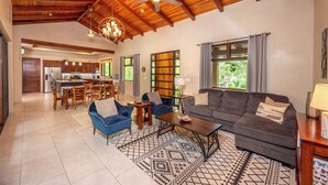 A spacious living area with a high ceiling, a dining area, and a kitchen.