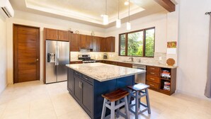 A modern kitchen with a large island, stainless steel appliances, and wooden cabinetry.