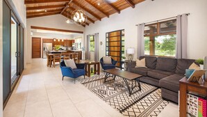 A spacious living area with a high ceiling, a dining area, and large windows.
