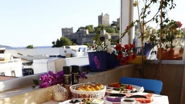 A dining table with a variety of dishes, a yellow chair, and a view of the cityscape. - Can Hotel (Bodrum)