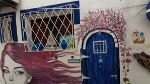 A building with a blue door, a 'Welcome' sign, and a mural of a woman's face. - Can Hotel (Bodrum)