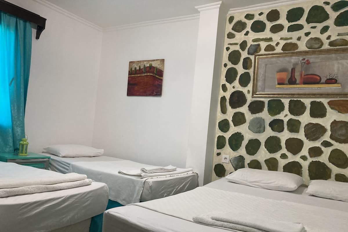 Habitación de hotel con dos camas, una mesita de noche, un cuadro y una pared con diseño de piedra.