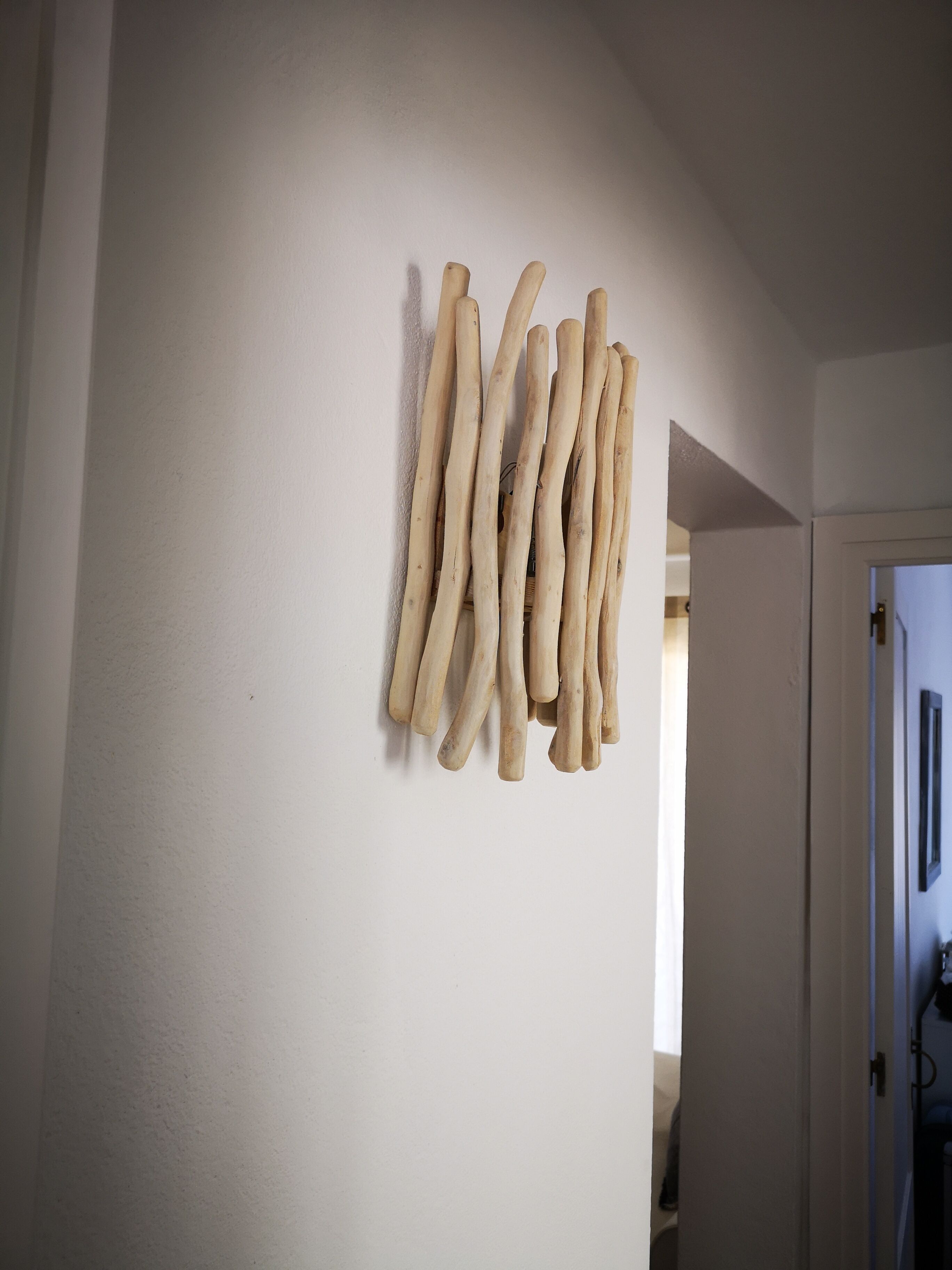 A hallway with a white wall and a door at the end.