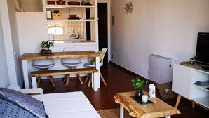 Een knus woongedeelte met een bed, een eettafeltje, een kitchenette en een televisie.