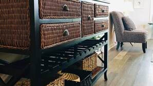 Een houten dressoir met gevlochten manden, een stoel en wanddecoraties in een kamer met houten vloer.