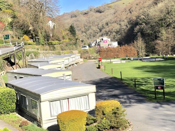A campsite with caravans, a grassy area, and a hill in the background.