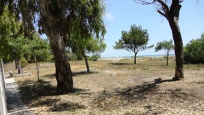 A paved pathway leading to a grassy area with trees and a view of the sea. - VersoSud - Apartment Vicino Spiaggia 04 (Ugento)
