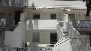 A multi-story building with a white exterior, multiple windows with metal grilles, and a staircase leading to the upper floors. - VersoSud - Apartment Vicino Spiaggia 04 (Ugento)