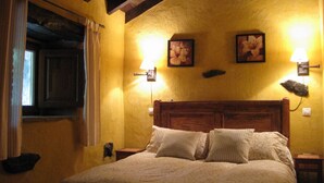 A bedroom with a wooden headboard, two wall-mounted lamps, and two framed pictures. - Charming cottage in the valleys pasiegos. Stunning views of the mountains. (San Roque de Riomiera)