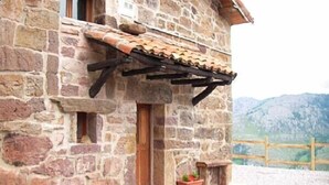A stone building with a wooden door and windows, a tiled roof, and a gravel driveway. - Charming cottage in the valleys pasiegos. Stunning views of the mountains. (San Roque de Riomiera)