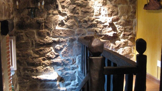 A stone-walled corridor with a wooden railing and a hanging light fixture. - Charming cottage in the valleys pasiegos. Stunning views of the mountains. (San Roque de Riomiera)