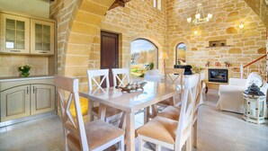 A stone-walled dining area with a table and chairs, a fireplace, and a view of the outdoors.