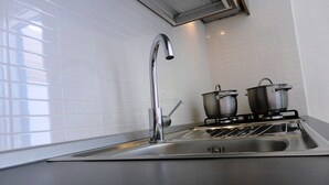 Une cuisine moderne dotée d’un évier en acier inoxydable, d’un robinet et d’une cuisinière à gaz avec des casseroles.