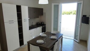 Une cuisine moderne avec des meubles blancs, un plan de travail foncé et une table à manger pour quatre personnes.