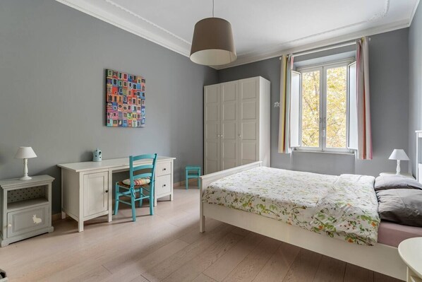 A bedroom with a bed, a desk, a chair, a wardrobe, and a window with curtains. - Walking to Trastevere (Roma)