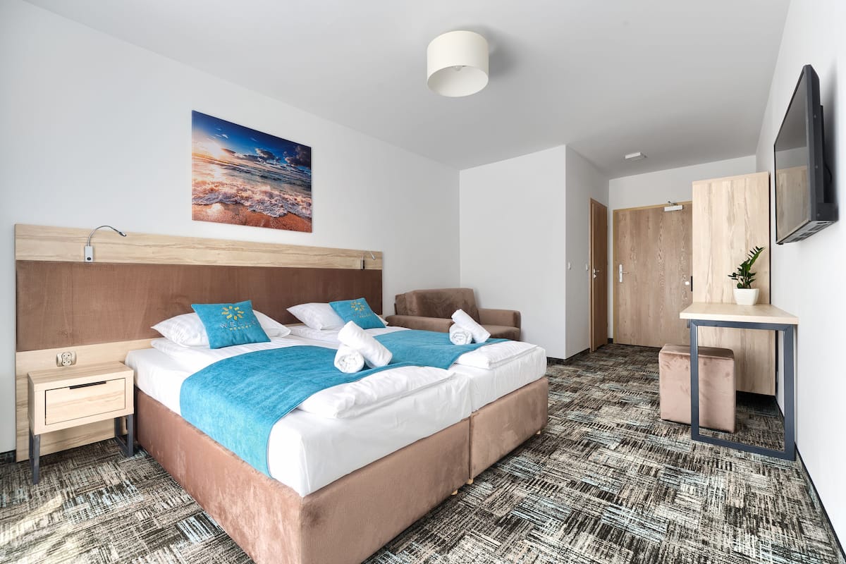 A modern hotel room with a large bed, a desk, a chair, and a television.