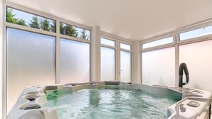 Un jacuzzi con vista a árboles a través de ventanas empañadas.