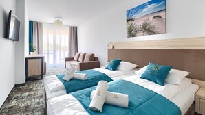 Habitación de hotel con dos camas, televisor, escritorio y ventana con cortinas.