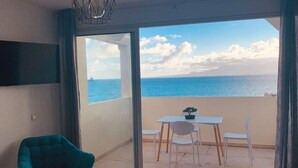 Et værelse med en skydedør, der fører ud til en balkon med havudsigt.