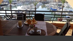 A balcony with a table set for breakfast, overlooking a marina with boats and buildings. - HEC Beach Apartment Marina Vilamoura, sea side, pool, golf, beach, boat trips,  (Quarteira)