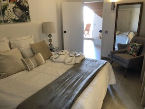 Ein Schlafzimmer mit einem Bett, einem Sessel, einer Lampe und einem Spiegel.